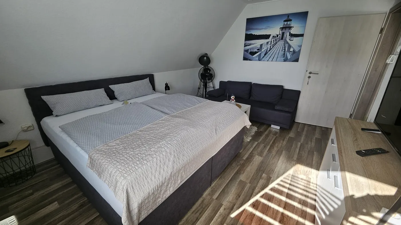 Schlafzimmer mit Doppelbett, Fernseher und Leuchtturm an der Wand
